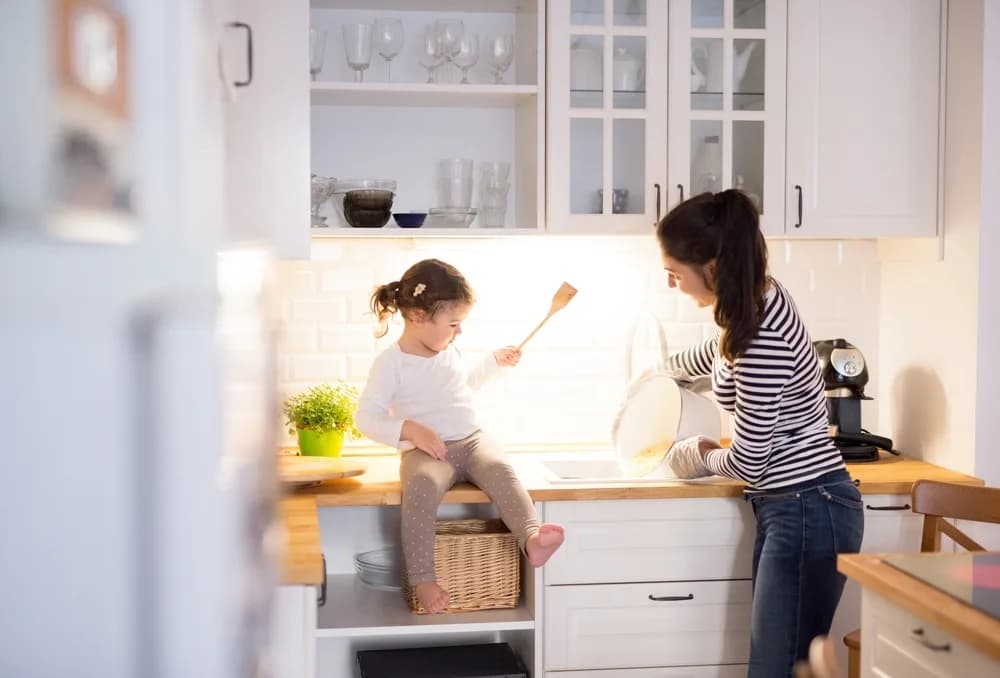 Mother and toddler daughter in kitchen baking