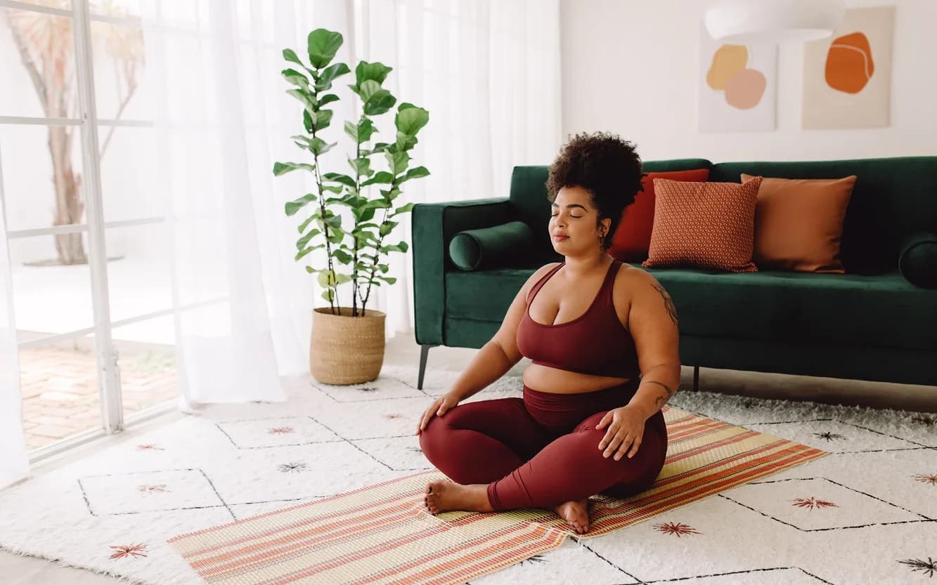 Woman meditating in yoga pose relaxing at home