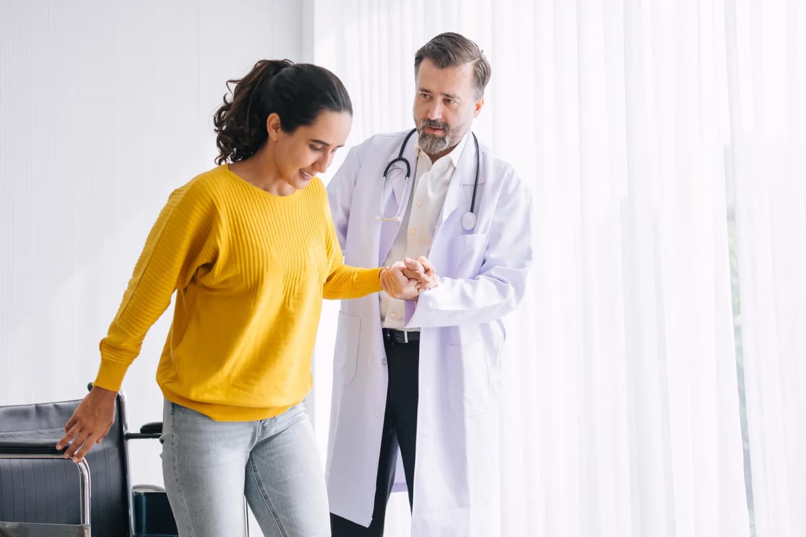 Doctor assisting patient from wheel chair