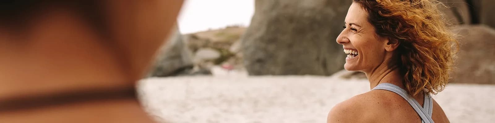 Two women sitting on beach smiling