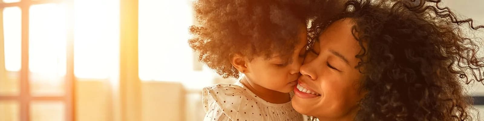 Mother and infant daughter smiling and embracing